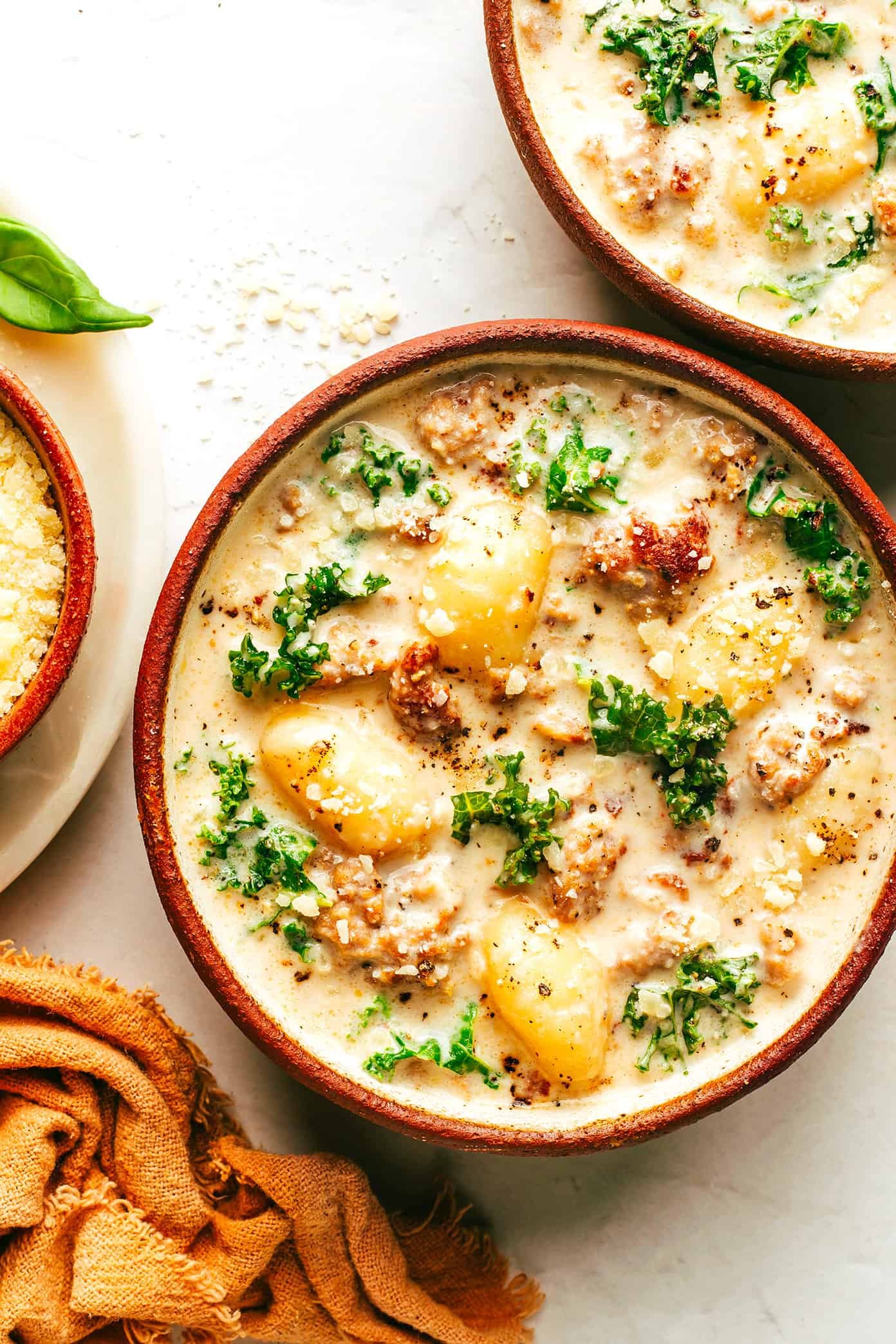 Homemade zuppa toscana soup with kale, potatoes and bacon served in red bowls