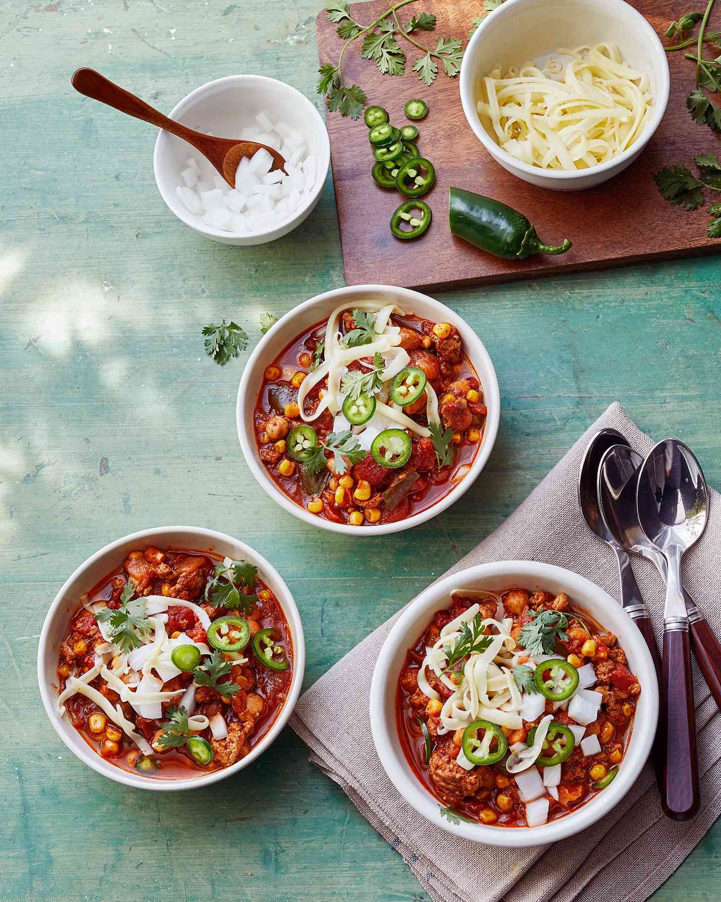 Instant pot turkey chili topped with cheddar cheese and served in white bowls