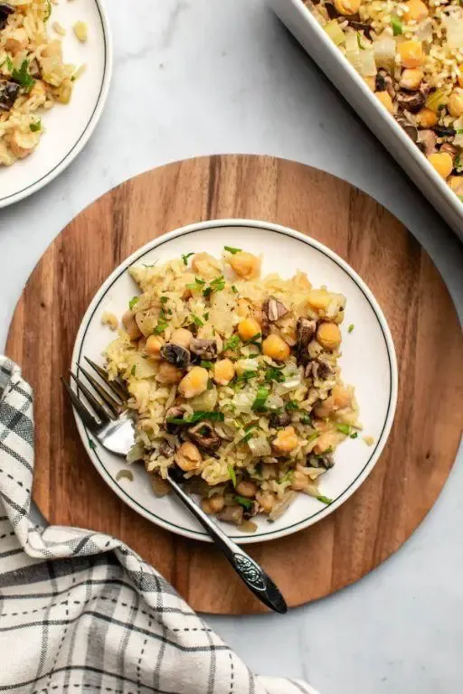 Home chickpea rice recipe with mushrooms, white round plate and wooden chop board