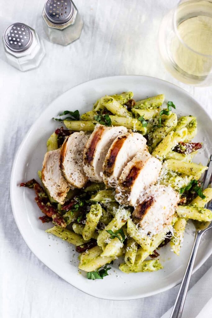 Chicken pesto pasta with sundried tomatoes and grated parmesan cheese