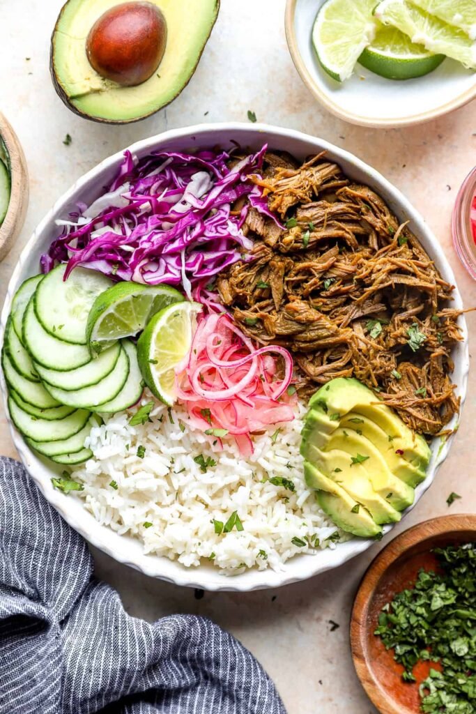 delicious shredded beef bowl, homemade with rice, red cabbage, sliced avocado and sliced cucumber.
