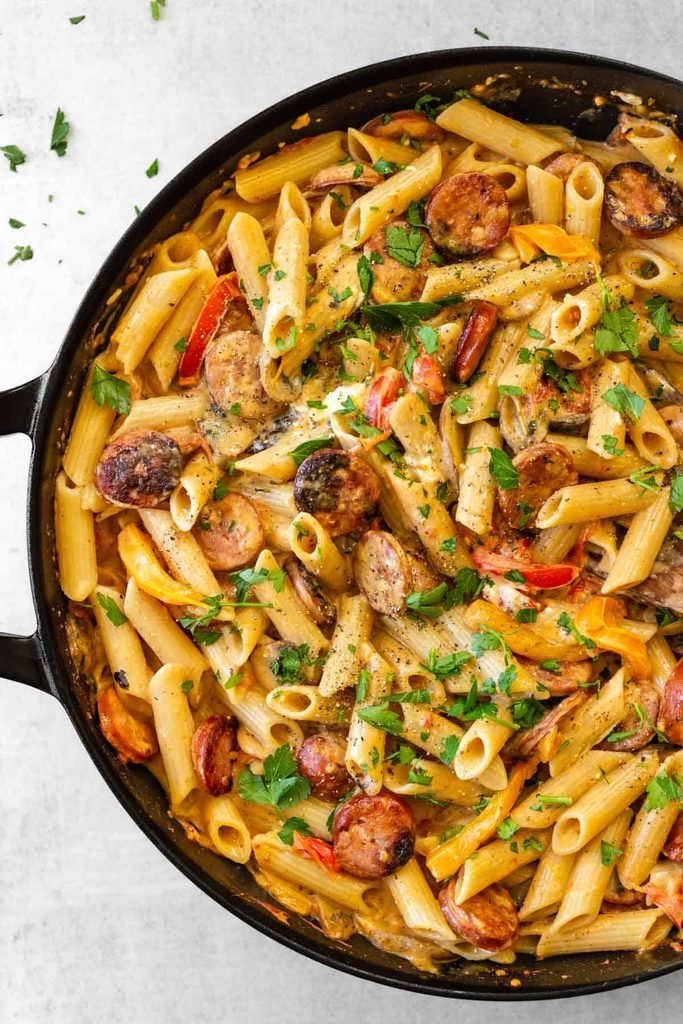 easy one pot cajun beef pasta made with sausages made in a black skillet, garnished with parsley.