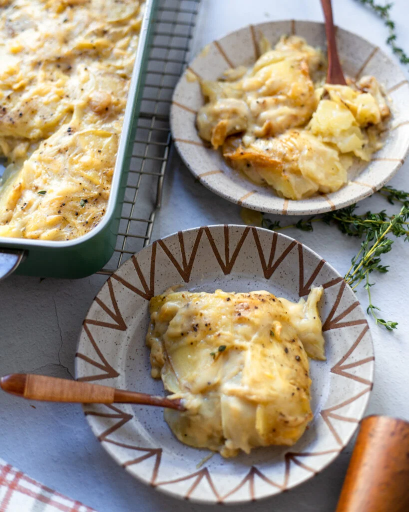 Vegan Potato gratin baked in a green rectangle serving dish and 2 portions served in 2 small plates 