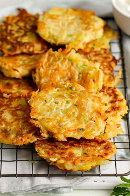 crispy cabbage fritters stacked on a stainless steel tray